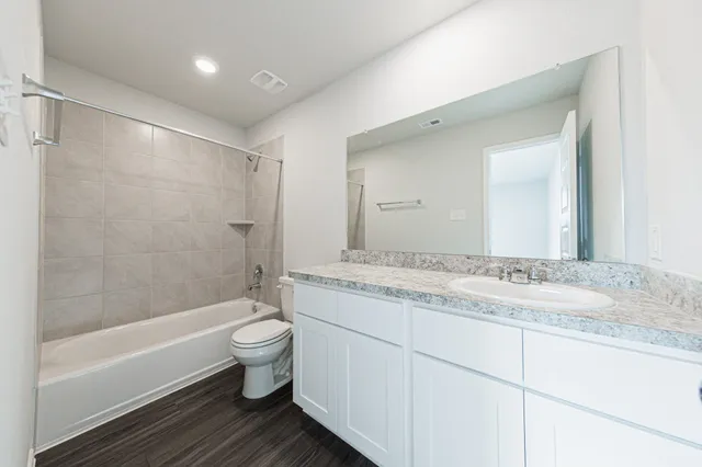 a bathroom with a granite countertop sink a toilet and shower