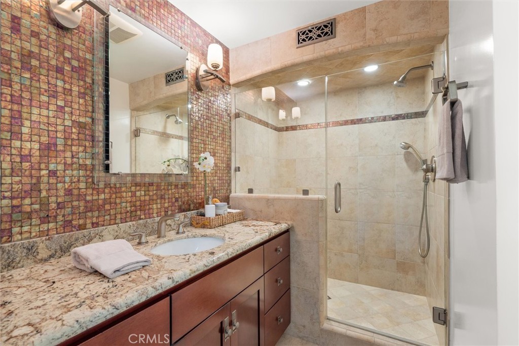 6301 East Bixby Hill Road Long Beach, CA 90815 - Photo 16 of 48 a bathroom with a granite countertop sink a mirror and shower