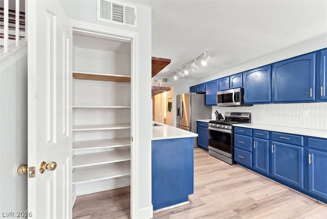 505 Rafkin Place Henderson, NV 89052 - Photo 8 of 35 Ample pantry storage and sleek blue cabinetry elevate this well-appointed kitchen.