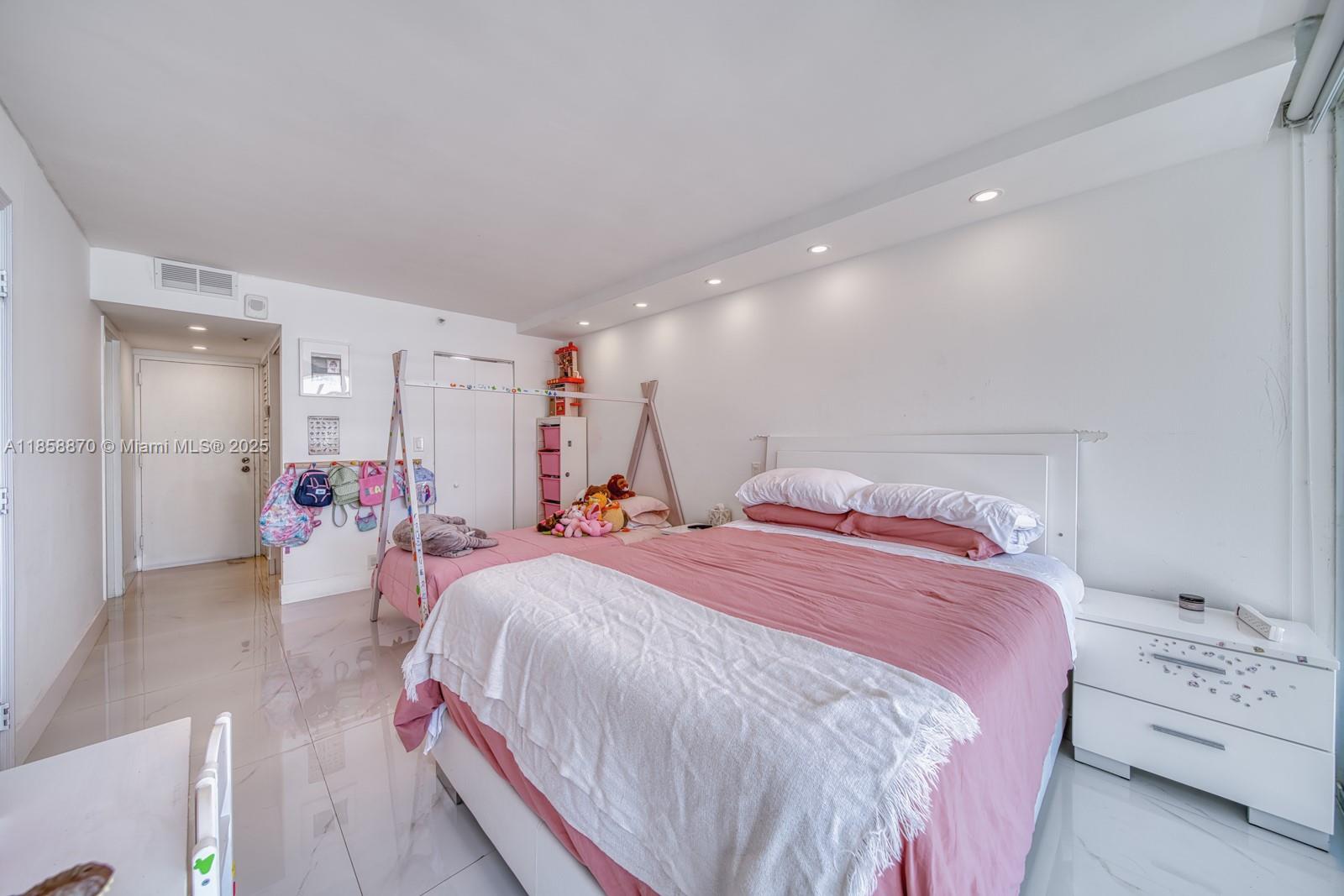 7601 East Treasure Drive, Unit 2424 North Bay Village, FL 33141 - Photo 23 of 25 a spacious bedroom with a bed and a lamp