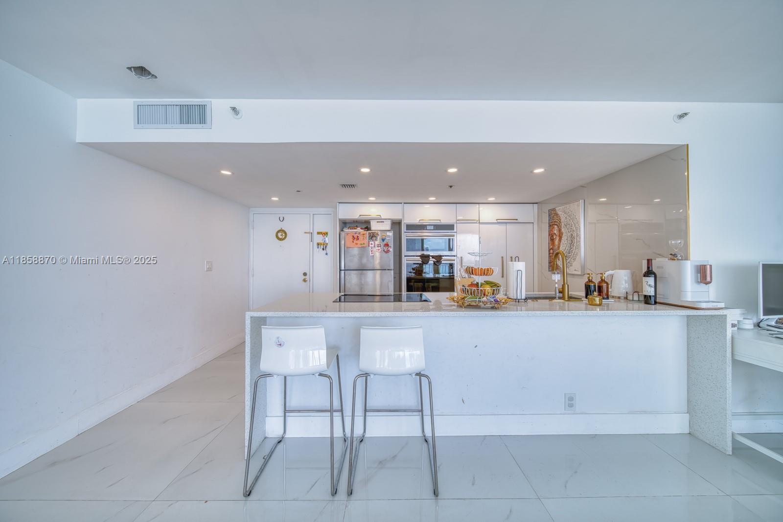 7601 East Treasure Drive, Unit 2424 North Bay Village, FL 33141 - Photo 8 of 25 a kitchen with a sink counter and chairs