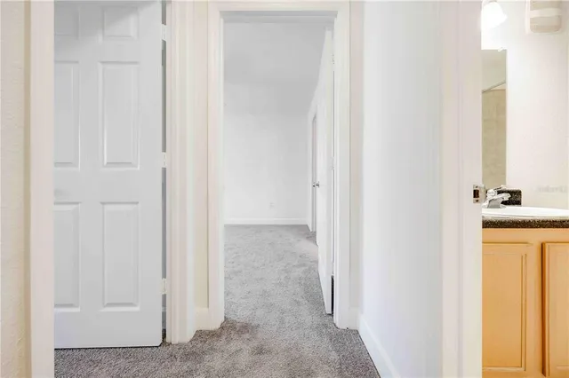 a view of a hallway with wooden floor and a bathroom