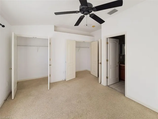 an empty room with closet and a ceiling fan