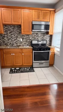 a kitchen with granite countertop a stove top oven cabinetry a chimney and a sink