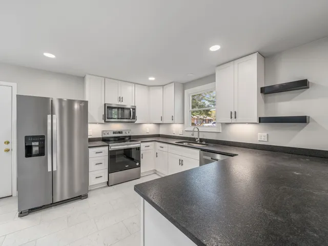 a kitchen with stainless steel appliances granite countertop a refrigerator a stove top oven a sink and cabinets