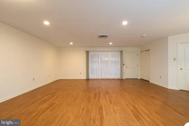 a view of an empty room with wooden floor and closet