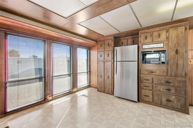 a view of a refrigerator in kitchen and an empty room