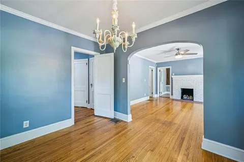 a view of an empty room with chandelier and fireplace