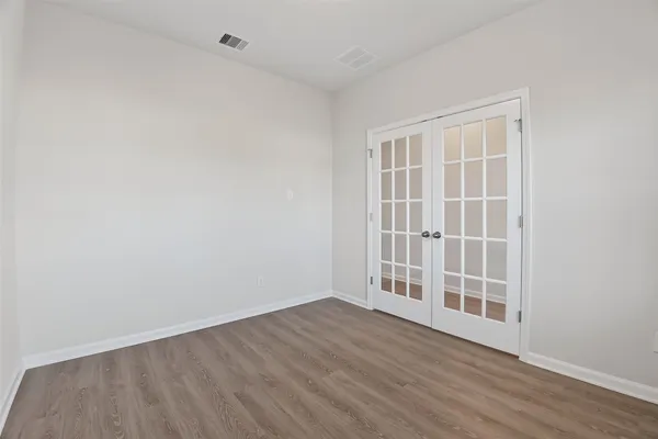 an empty room with wooden floor and windows