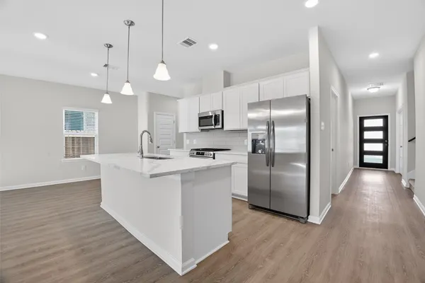 a kitchen with stainless steel appliances granite countertop a refrigerator a sink dishwasher a oven and a large with wooden floor