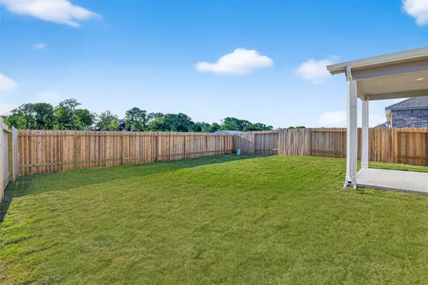 a view of a backyard with grass & fence
