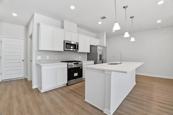 a kitchen with a sink a microwave a stove and a wooden floors