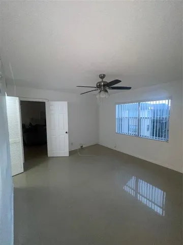 an empty room with a ceiling fan and window