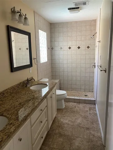 a bathroom with a granite countertop sink a toilet and shower