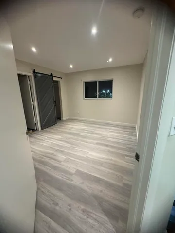 a view of an empty room with wooden floor and a window