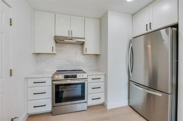 a kitchen with refrigerator a stove and white cabinets