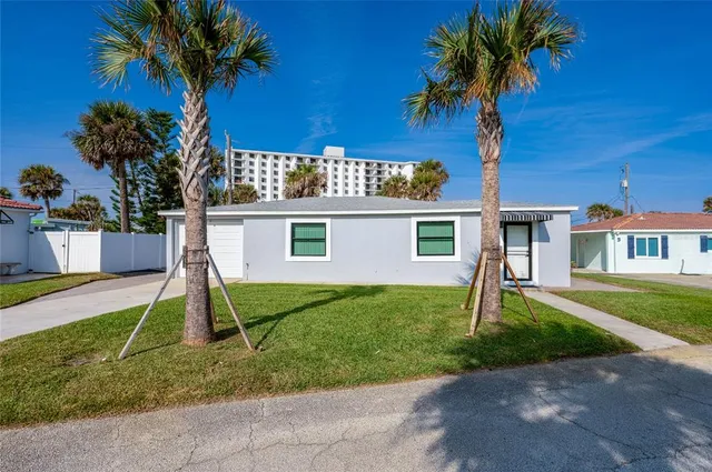 a view of a house with a yard and palm trees