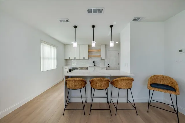 a view of a kitchen with kitchen island granite countertop wooden floor and white cabinets