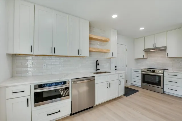 a kitchen with granite countertop white cabinets and stainless steel appliances