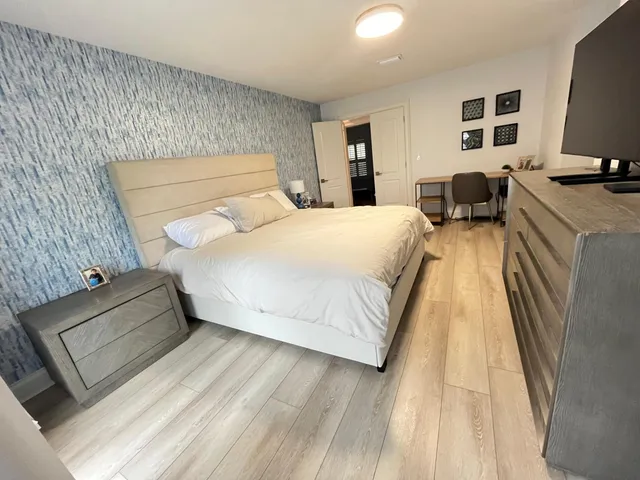a bedroom with a bed and a flat tv screen on dresser