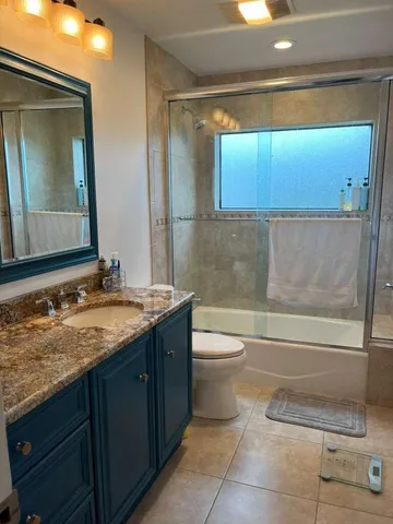 a bathroom with a granite countertop sink toilet and shower