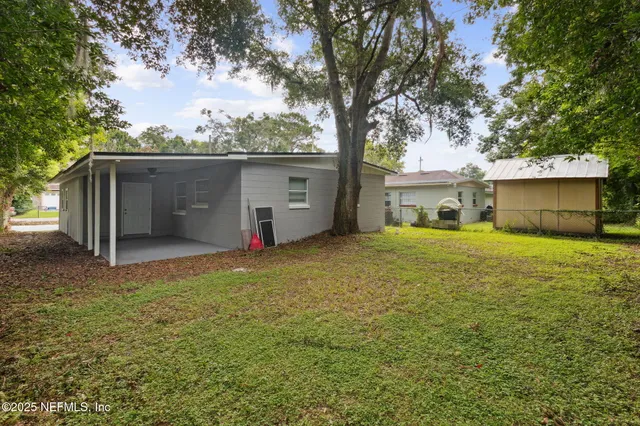 a view of a house with backyard and a tree