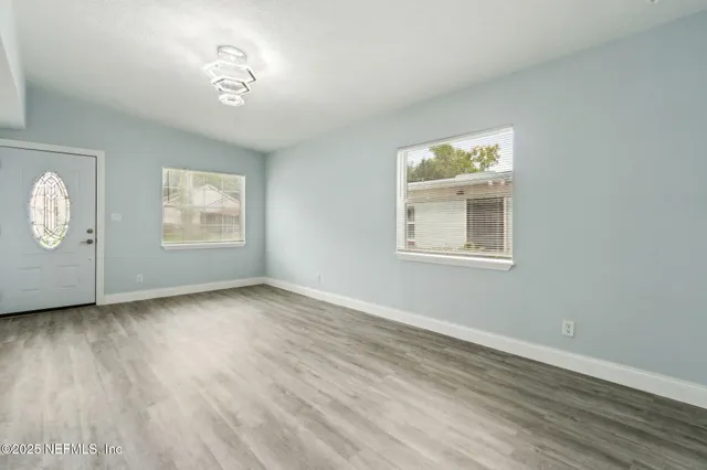 a view of an empty room with a window and wooden floor