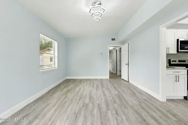 a view of empty room with wooden floor and fan