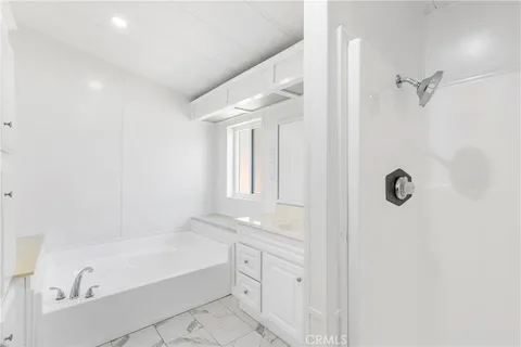 a bathroom with a tub shower vanity and a sink