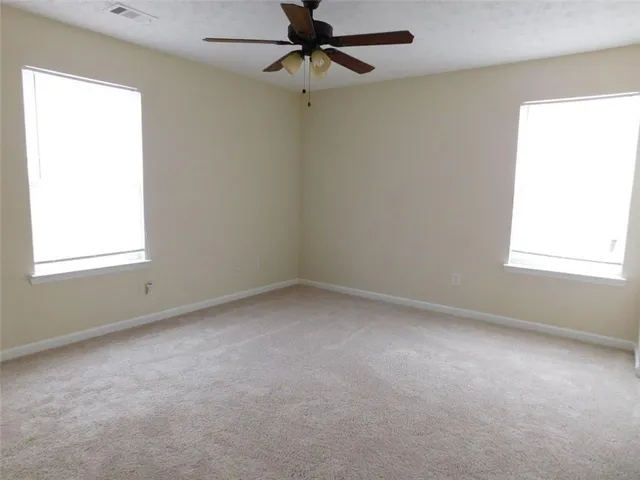 an empty room with a window and a fan