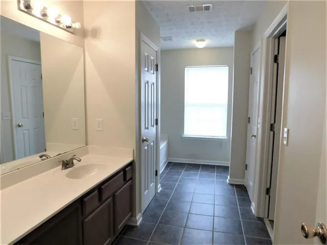 a bathroom with a double vanity sink a mirror and a bathtub