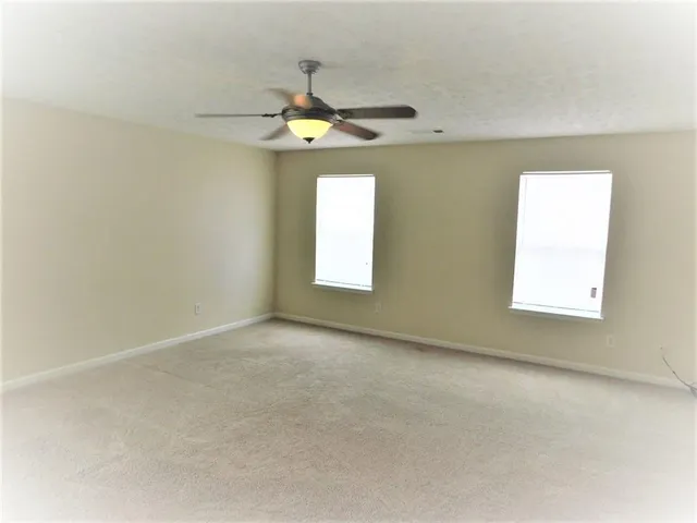 an empty room with a window and a ceiling fan