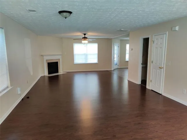 an empty room with wooden floor fireplace and windows