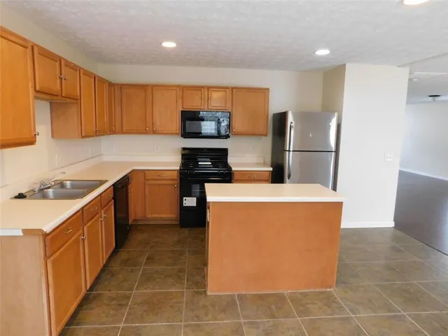 a kitchen with stainless steel appliances a refrigerator a sink a stove top oven a counter space and cabinets