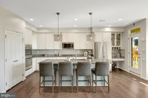 a kitchen with stainless steel appliances kitchen island granite countertop a table chairs and a refrigerator