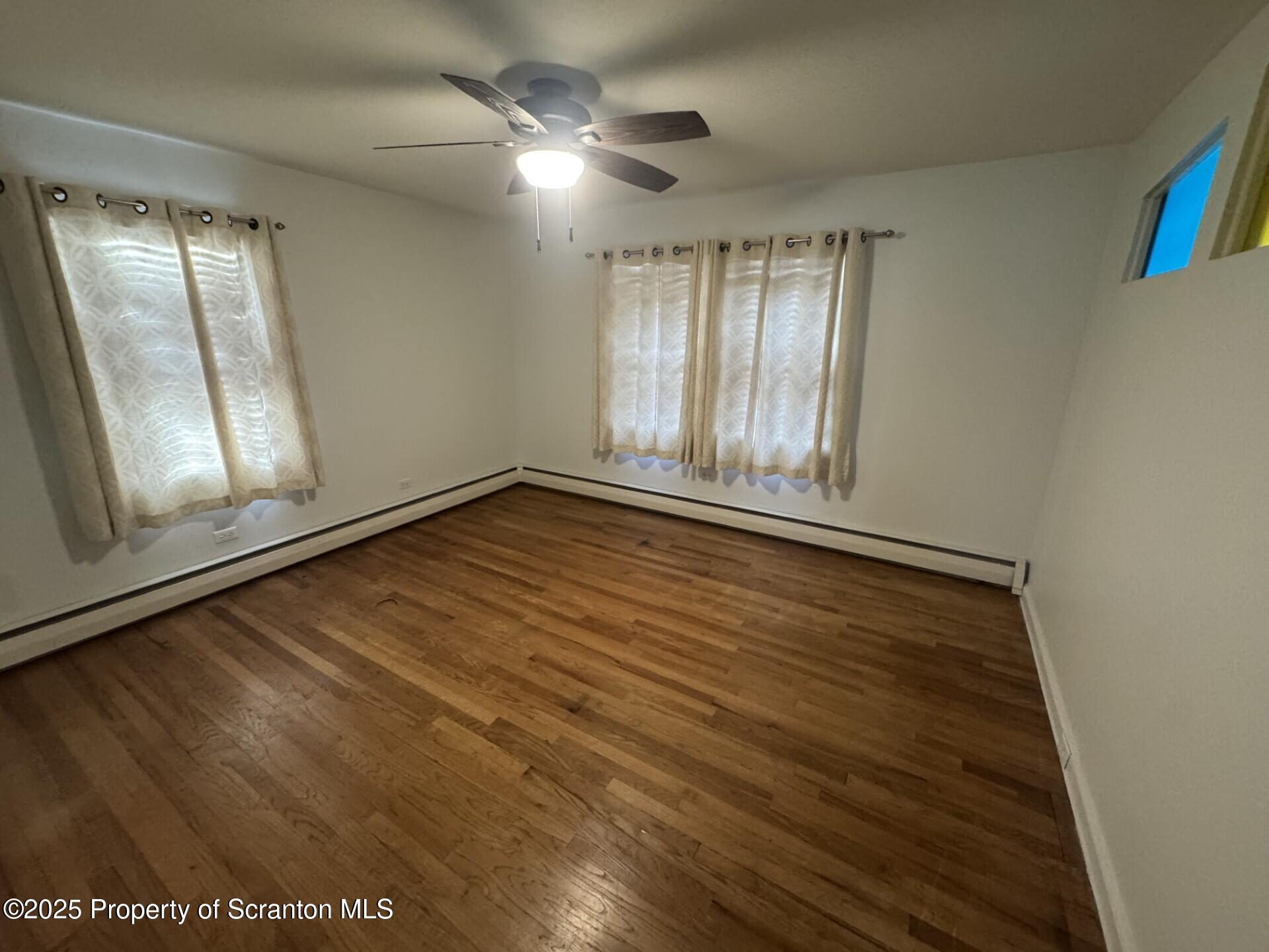 910 Bernard Avenue Clarks Summit, PA 18411 - Photo 9 of 17 an empty room with wooden floor fan and windows