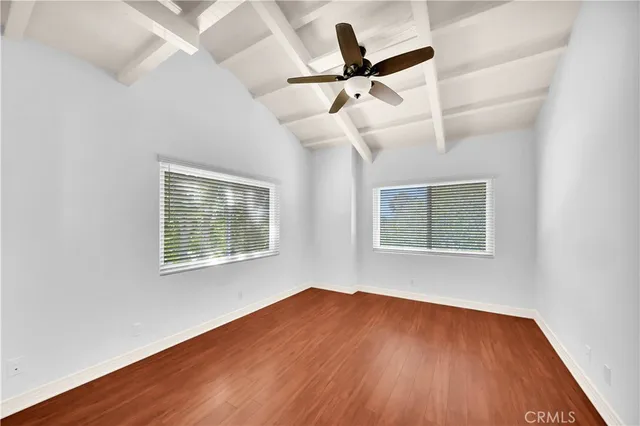 an empty room with wooden floor ceiling fan and windows