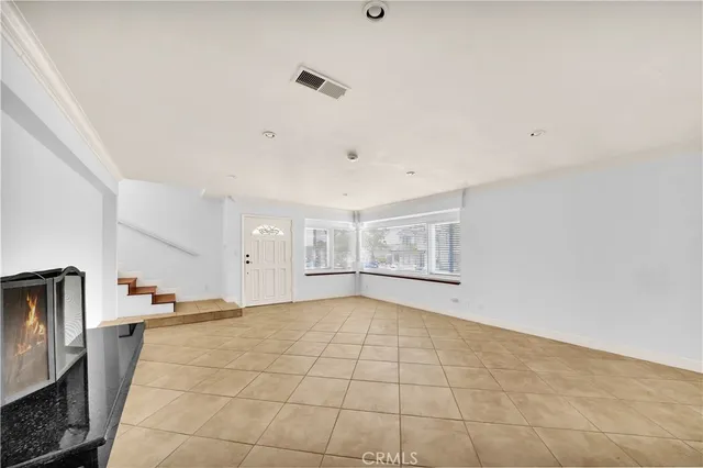 a view of an empty room with window and chandelier