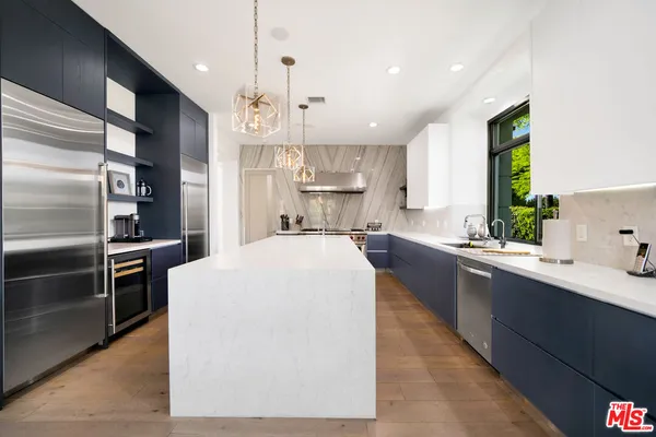 a kitchen with kitchen island a counter top space a sink stainless steel appliances and cabinets