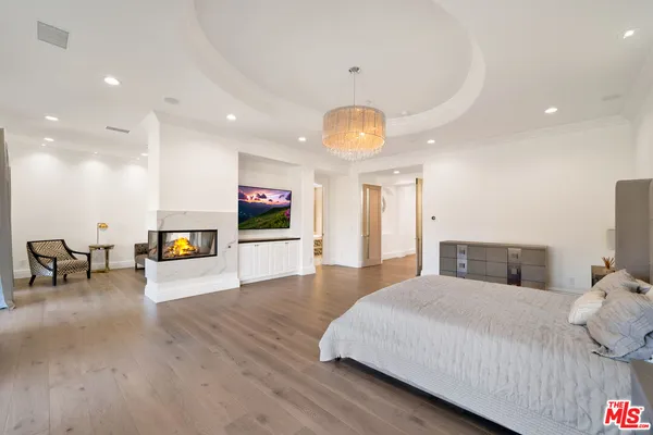 a spacious bedroom with a large bed and a chandelier