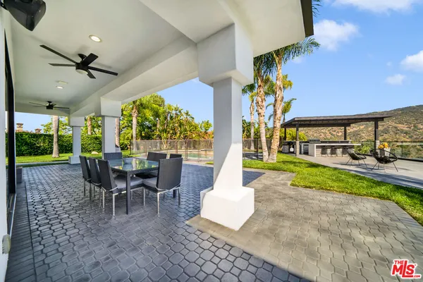 a view of a patio with table and chairs potted plants with floor to ceiling window