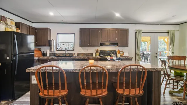 a kitchen with stainless steel appliances granite countertop a refrigerator a stove a sink and a dining table with garden view