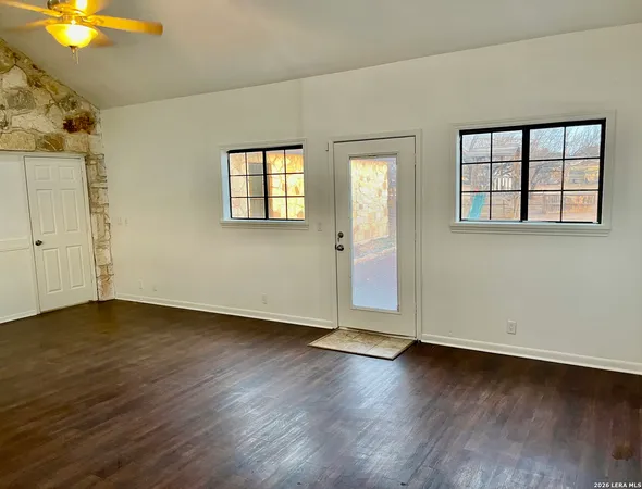 an empty room with wooden floor and windows