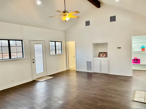 a view of an empty room with window and wooden floor