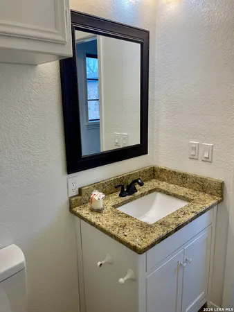 a bathroom with a granite countertop sink and a mirror
