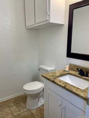 a bathroom with a granite countertop toilet sink and mirror