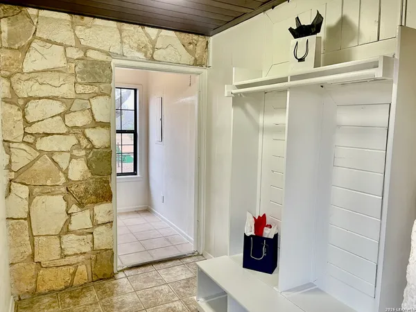 a hallway with a white cabinet a mirror and shower
