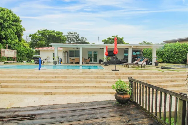 a view of a white house with a swimming pool and outdoor seating