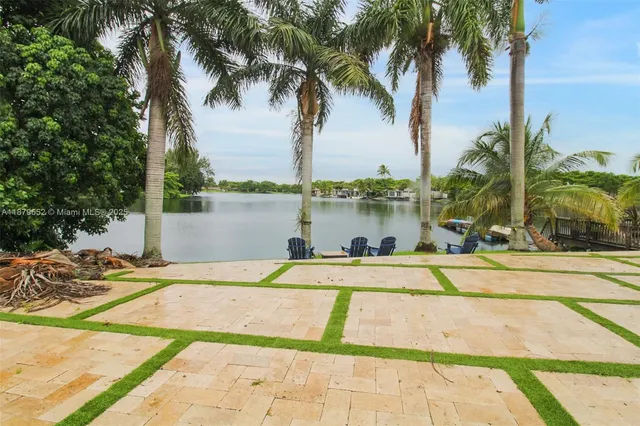 a view of a swimming pool with a lawn chairs under palm trees