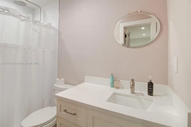 a bathroom with a sink vanity mirror and toilet